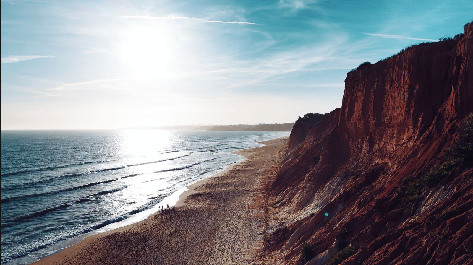 Ochre cliffs rising above the sand and Atlantic at Falésia